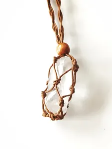 Macro view of a raw clear crystal stone pendant within a brown hand-woven net pouch.