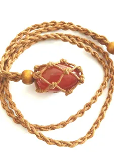 Close-up of hand-woven net necklace with polished reddish-orange natural stone pendant