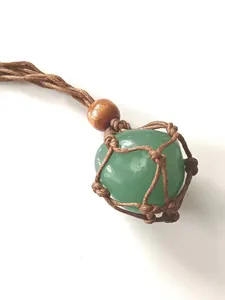 Close-up of green crystal stone pendant in handmade woven brown net pouch necklace