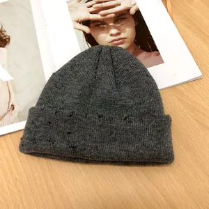 Gros plan d'un bonnet en maille gris foncé avec des détails usés sur le revers.