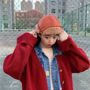 Stylish orange winter landlord hat with plush earflaps shown on a female model outdoor
