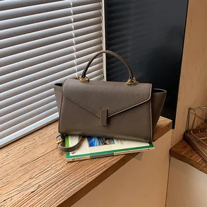 Elegant dark taupe textured leather handbag placed on a wooden windowsill setting