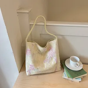 New Chinese style bucket bag with floral embroidery and braided handle in a lifestyle setting.