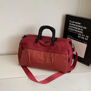 Detailed side view of a stylish red travel duffel bag with a front grid pattern pocket