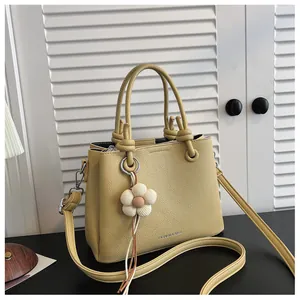 Vista detallada de un elegante bolso cubo amarillo de cuero granulado con adorno de flor