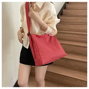Detailed view of the red checkered nylon crossbody bag being worn in a casual setting