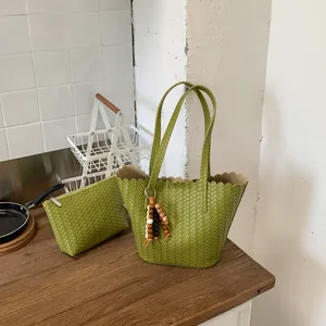 Fashionable green woven bucket bag with matching pouch shown in a stylish kitchen setting