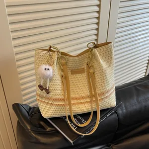 Detailed view of cream woven tote bag with stripe pattern and gold chain handles