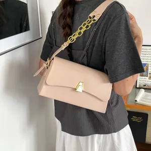 Model wearing a stylish beige small square shoulder bag with a gold chain strap detail.