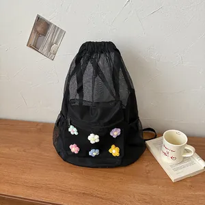 Detail of black mesh drawstring backpack with colorful knit flower appliques on wooden desk