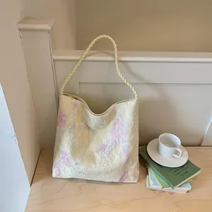 Detail view of the intricate pink floral embroidery on a yellow Chinese style bucket bag