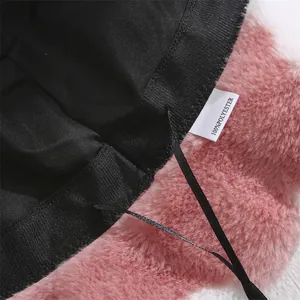 Detail view of plush bucket hat showing 100% polyester care label and black lining.