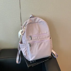 Mochila minimalista de color morado claro estilo coreano para mujer sobre un libro decor