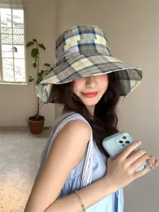 Sombrero de pescador a cuadros con ala ancha para protección solar, modelo en escena de estilo.