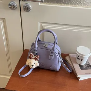 Detailed view of purple Boston handbag with textured leather and cute dog charm