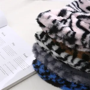 Détail de chapeaux bobs en peluche à motif zèbre empilés de couleurs variées.