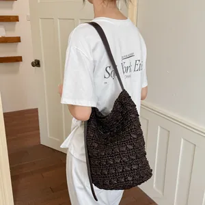 Detailansicht einer dunkelbraunen, handgehäkelten Beuteltasche, über der Schulter getragen.