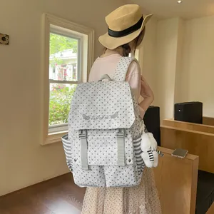 Back view of a grey star pattern backpack with a cute bear charm worn by a model