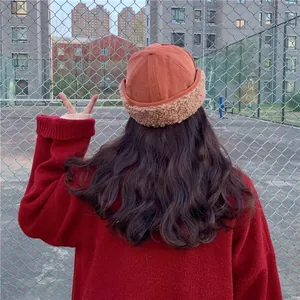 Rear view of a stylish woman wearing a warm rust-colored docker hat with thick plush sherpa brim