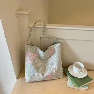 Detailed view of the floral embroidery and braided strap on the sage green bag