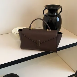 Detailed view of brown textured leather handbag with gold-tone hardware clasp.