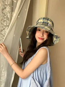Modelo asiática con un elegante sombrero de cuadros con ala ancha para verano.