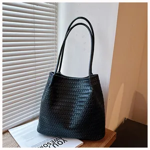 Detailed view of a retro black woven leather tote bag with long dual shoulder straps.