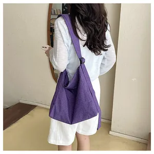 Detailed lifestyle shot of a purple checkered crossbody bag worn over the shoulder.