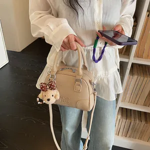 Detailed view of a stylish beige Boston handbag featuring a cute plush dog charm accessories