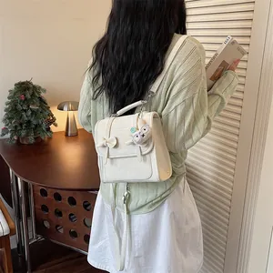 Modella indossa un elegante zainetto bianco preppy con ciondolo a coniglietto decorativo