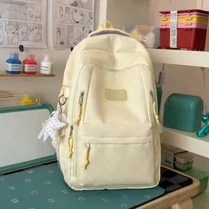 Detailopname van een pastelgele rugzak met schattige witte strikpatronen en een sterbedeltje