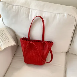 Detailed view of a stylish red woven bucket bag with unique scalloped edges on a cozy sofa