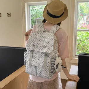 Women's stylish grey star pattern backpack with plush bear keychain shown on model