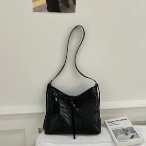 Λεπτομέρεια μαύρης χειροποίητης πλεκτής τσάντας ώμου με λεπτή υφή και μακριά λουριά