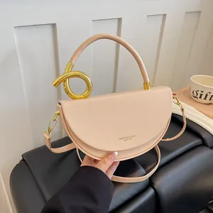 Detailansicht einer eleganten beigen Satteltasche mit einem einzigartigen Goldgriff.