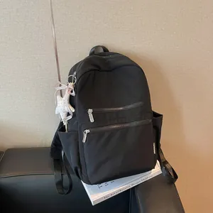 Vista lateral de mochila negra minimalista con bolsillos y colgante de estrella deco