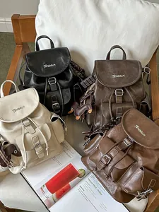 Set of four stylish women's leather backpacks in multiple colors displayed on a chair.