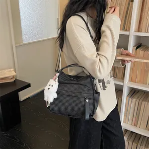 Stilvolle schwarze Gitter-Umhängetasche mit flauschigem Hundeanhänger am Modell