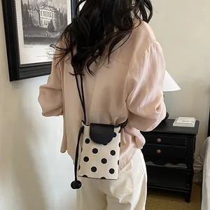 Back view of model wearing a stylish black and white polka dot crossbody phone bag