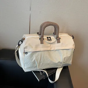 Detailed view of a beige travel bag with diamond pattern and brown handles on a black base.