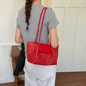 Detailansicht einer roten geflochtenen Tragetasche als Schultertasche an einem Model.