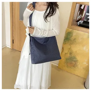 Large capacity blue checkered nylon crossbody bag worn by model in a casual setting