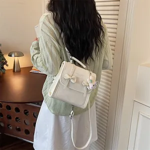 Dettaglio di uno zaino bianco stile preppy con fiocchi eleganti e un simpatico ciondolo morbido