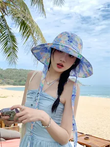 Detailansicht eines stylischen Blumen-Sonnenhuts mit Bindebändern an einem sonnigen Strand