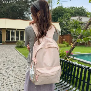Modischer hellrosa Rucksack mit Sternenprint, getragen von einem Model im grünen Garten