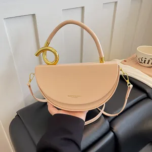 Nahaufnahme einer beigen Satteltasche mit einem einzigartigen goldfarbenen Knotengriff