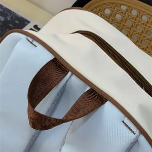 Close-up of durable cream and blue canvas backpack detail showing zipper and brown handle