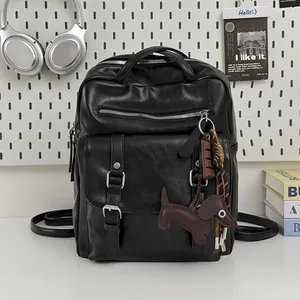 Detail view of a black large capacity travel backpack with a cute dog-shaped keychain.