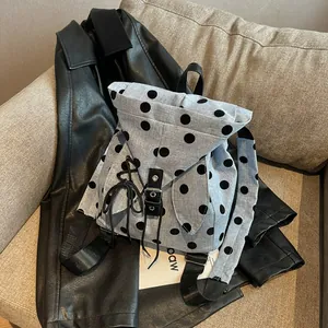 Casual light blue polka dot backpack for women shown on a stylish black leather jacket