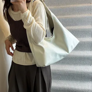 Detalle de un bolso vintage grande color crema llevado al hombro tipo hobo.